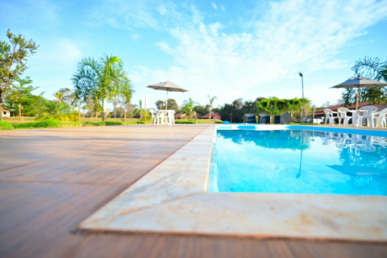 an empty swimming pool with chairs and umbrellas