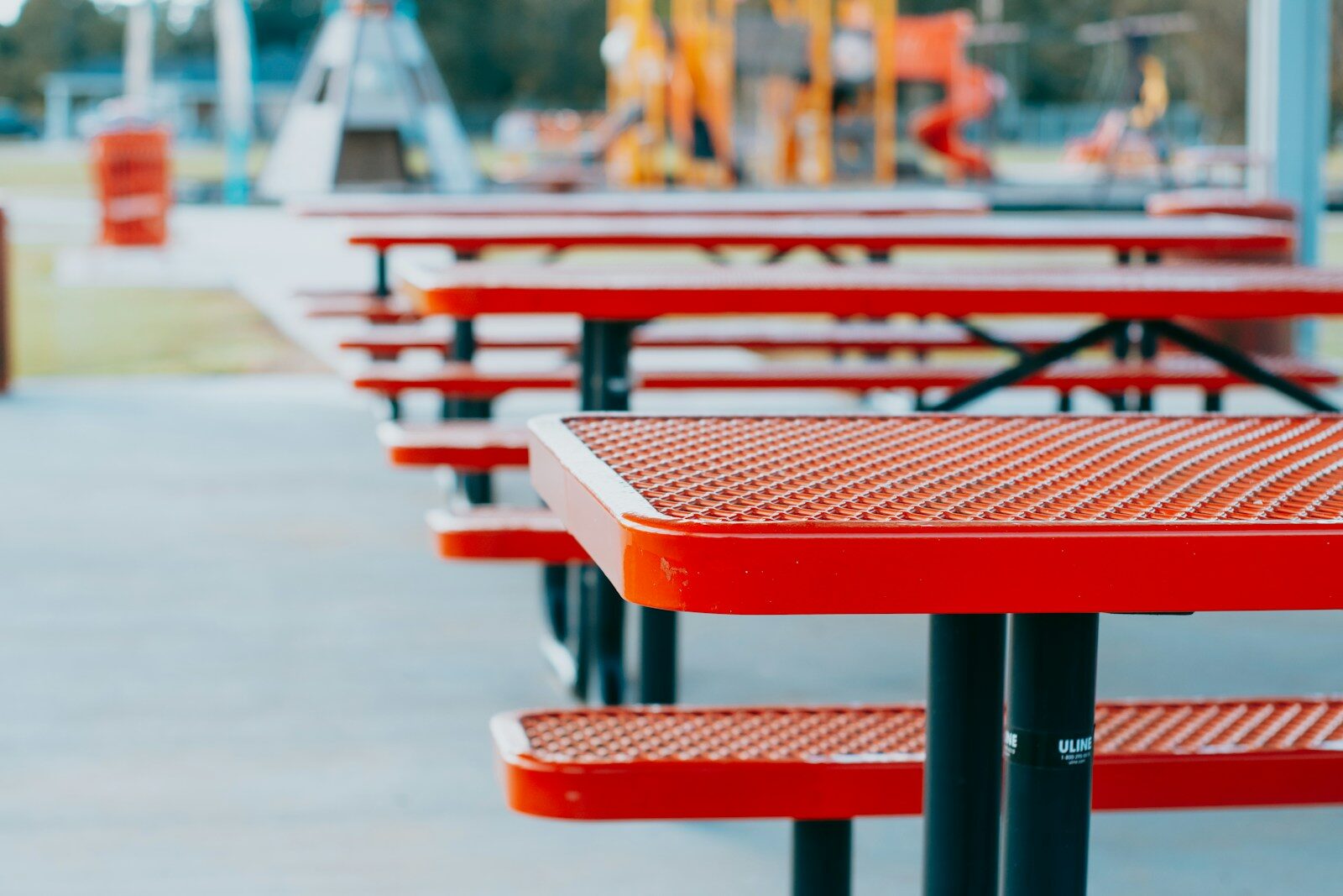 A row of red picnic tables sitting next to each other