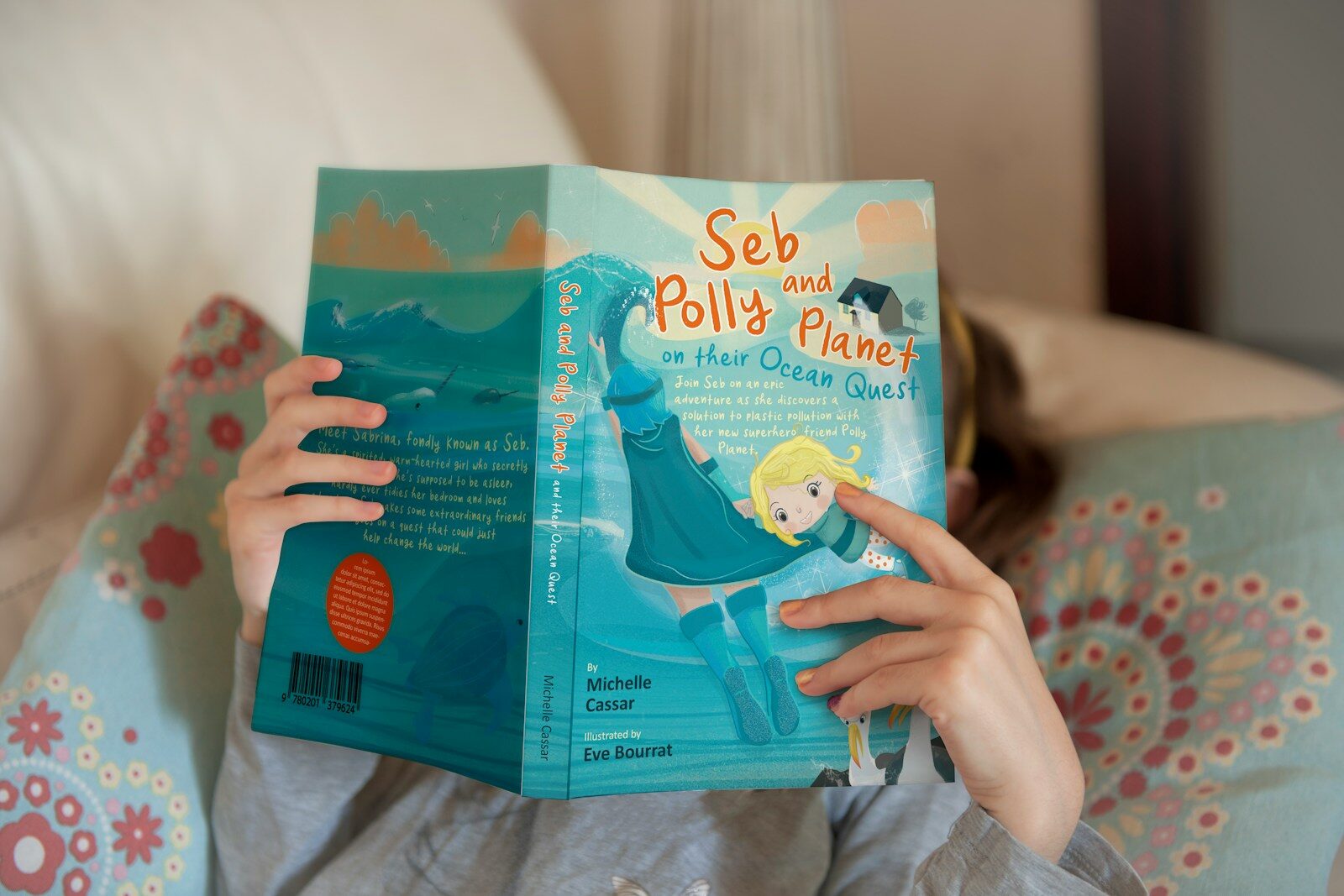 a little girl is reading a book on a couch